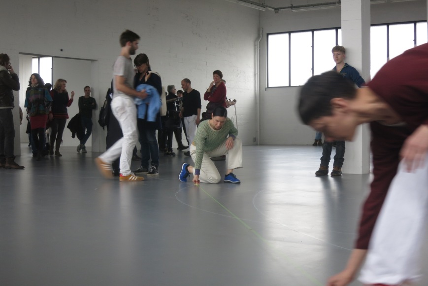 A dancer re-draws a chalk circle of the pattern guiding the dancers